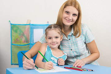 Image showing Five-year girl and young mother together paint a picture on a sheet of paper