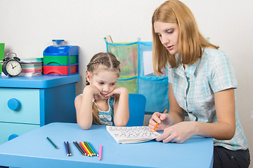 Image showing Five-year girl with interest looks at the teaching material explained by an adult