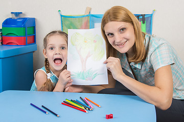 Image showing Five-year girl and the teacher happily show drawn on a sheet of wood
