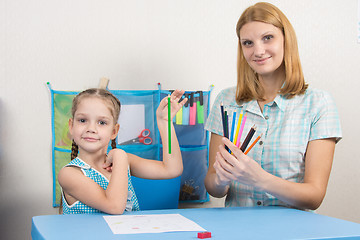 Image showing The five-year child chose the correct pencil from mother hands and looked into the frame