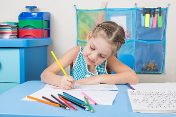 Image showing Happy five year old girl chose enthusiastically draws with colored pencils