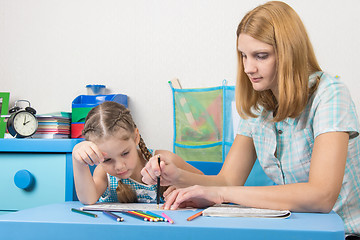 Image showing A girl interested look like mom paints a stencil