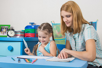 Image showing Girl enjoys painting with teacher in kindergarten