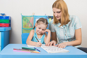 Image showing Young mother prepares a five-year girl to school