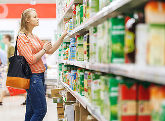 Image showing Young woman shopping for juice in supermarket