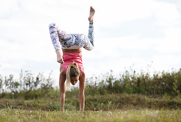 Image showing Agile young woman doing a handstand