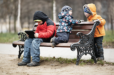 Image showing Three young boys playing on a park bench in winter