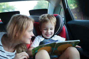 Image showing Boy holding book sitting in a car with mother