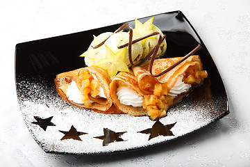 Image showing Golden pancakes with carambola and cream