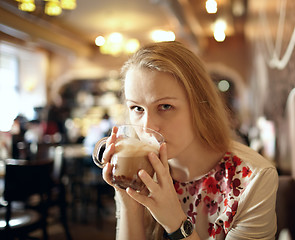 Image showing Girl is drinking latte in cafe.