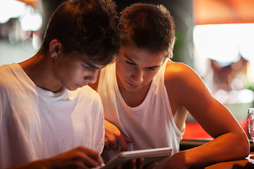 Image showing Young men using tablet computer in cafe