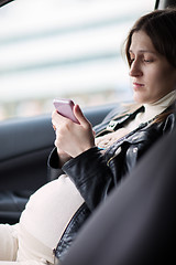 Image showing Pregnant woman texting on cell in the car