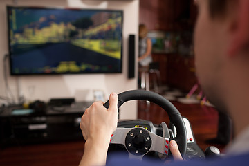 Image showing Man playing racing game with steering wheel simulator