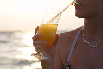 Image showing Woman sipping a refreshing cocktail at sunset