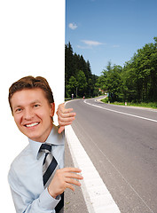 Image showing Smiling business man holding a image against white