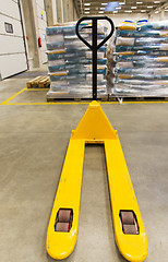 Image showing manual loader and cargo piles at warehouse