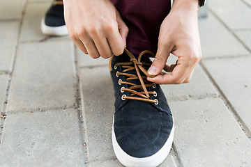 Image showing close up of male hands tying shoe laces on street