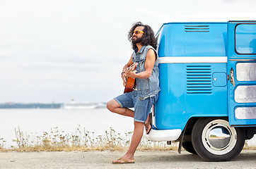 Image showing hippie man playing guitar over minivan on beach