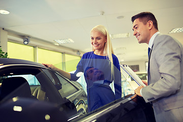 Image showing happy woman with car dealer in auto show or salon