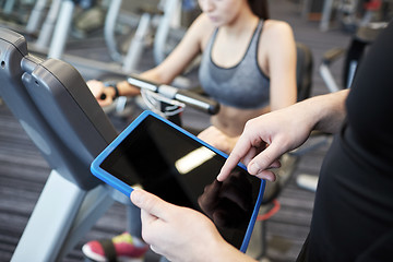 Image showing close up of trainer hands with tablet pc in gym