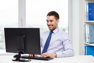 Image showing smiling young businessman with computer at office