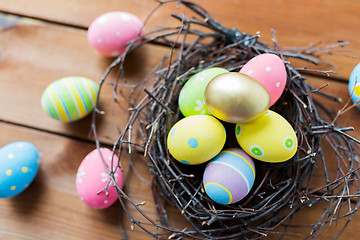 Image showing close up of colored easter eggs in nest on wood