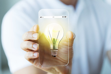 Image showing close up of hand with light bulb on smartphone