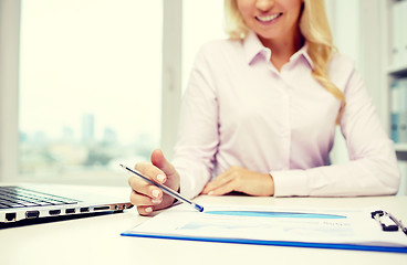 Image showing smiling businesswoman reading papers in office