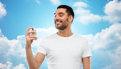 Image showing smiling man with male perfume over blue sky