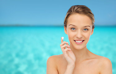 Image showing happy young woman applying cream to her face