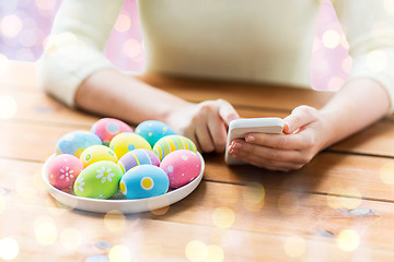 Image showing close up of hands with easter eggs and smartphone