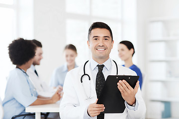 Image showing happy doctor with clipboard over medical team