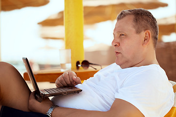 Image showing Man relaxing with a laptop at beach resort