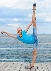 Image showing Smiling girl making stretching exercise by the sea