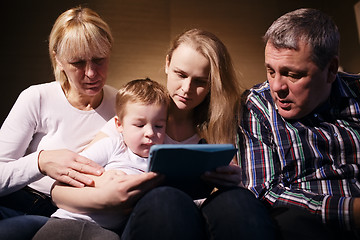 Image showing Family watching boy playing game on touchpad