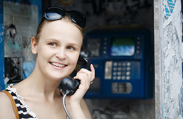 Image showing Attractive woman using a public telephone