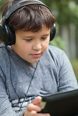 Image showing Teenager in headphones using pad outdoor