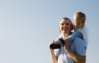 Image showing Young father giving his son a piggy back ride