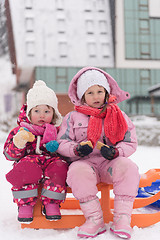 Image showing portrait of two little grils sitting together on sledges