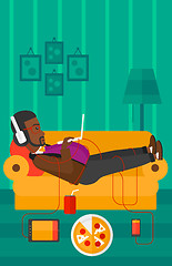 Image showing Man lying on sofa with many gadgets.