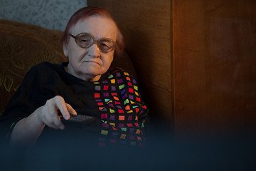 Image showing Old woman at home watching TV and changing channels