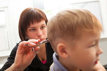 Image showing Hairdresser trimming a small boys hair