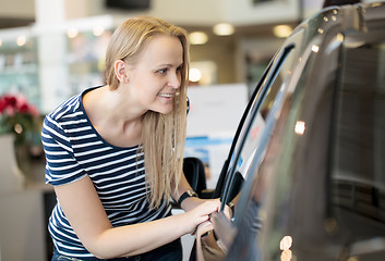 Image showing Woman admiring a car at an auto show