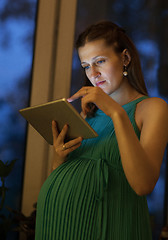 Image showing Serious pregnant woman using tablet at home