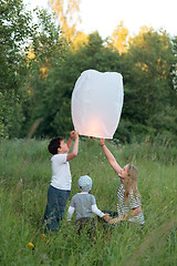 Image showing Family of three flying paper lantern outdoor