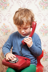 Image showing Small boy talking on a red telephone