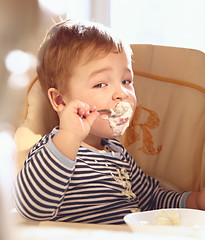 Image showing Two year old boy eats porridge in the morning.