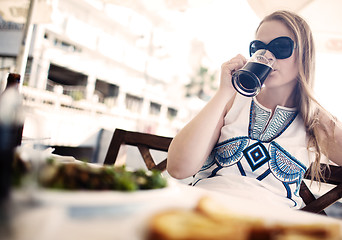Image showing Woman enjoying a dark beer with her meal