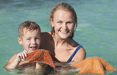 Image showing Mother and son in sea holding starfish