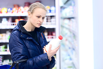 Image showing Woman in grocery holding milk